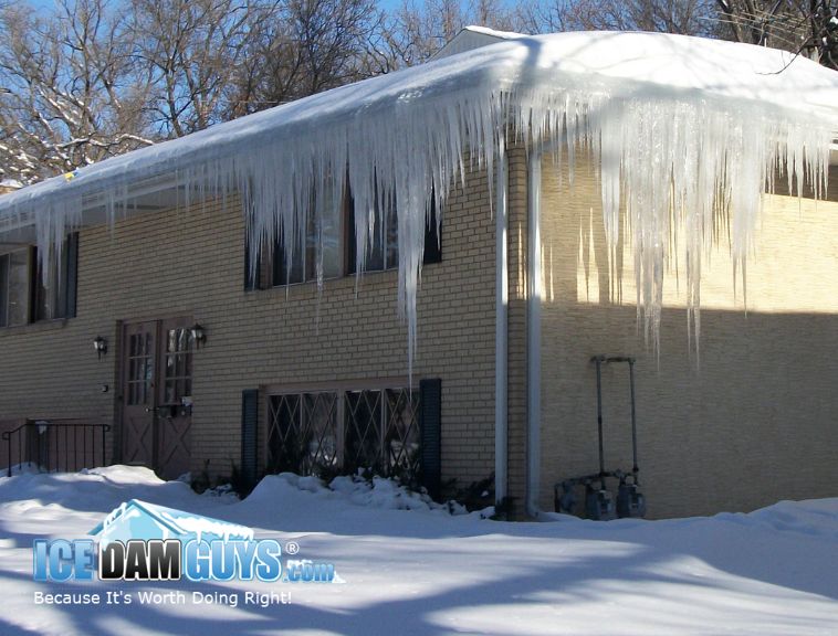 This photo shows a two-story brick home that has dozens of feet of large icicles and ice dams. One side of the home has over 20 feet and the other over 12 feet. Some of the icicles nearly reach the ground they're so long.