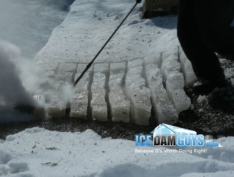 An Ice Dam Guys technician creates a grid pattern in a home's ice dam on their roof. He does this by using steam to cut the dam into smaller pieces that can easily, and safely, be removed from the roof.