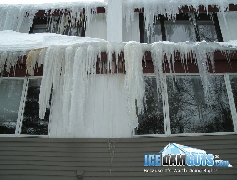 Ice Dam Guys help office buildings with ice dam removals. This photo shows a two-story professional office building with very large icicles and ice dams hanging over the gutters. It's clear they need help.