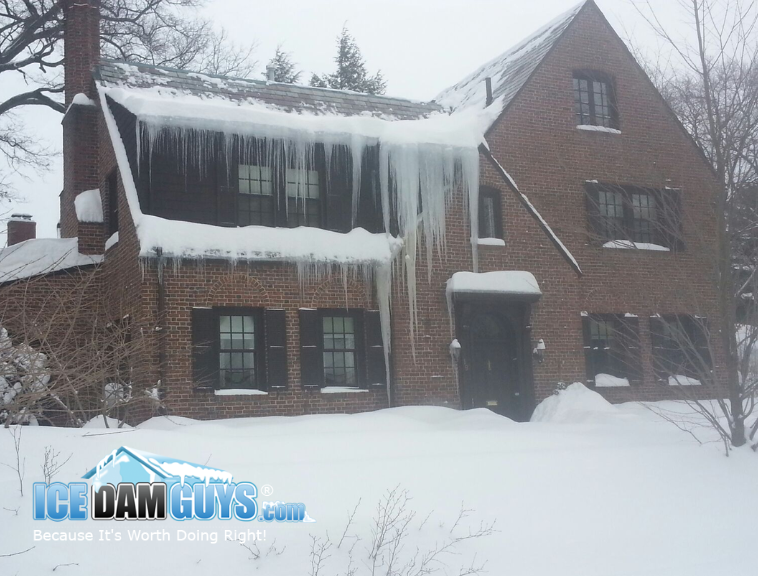 This image is of a brick home from that was likely build a couple of generations ago. it has steep roof lines and looks older but very regal and well built. It has incredibly long icicles from an ice dam hanging off the front roof. Some are well over 10 feet long and it's quite impressive!