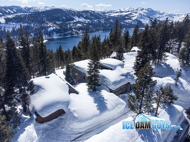 This photo is of homes bordering the perimeter of Lake Tahoe in California. It's winter and there are several feet of snow on each home's roof.